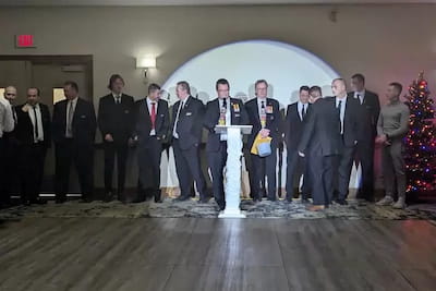 Formal group standing behind a podium at a holiday event in Manitoba